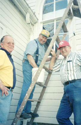 Three men from our church working outside with a ladder.
