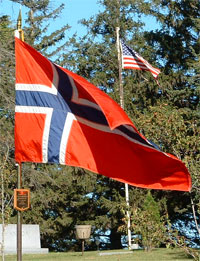 A picture of an American and Norwegian flag on the hill near the church.